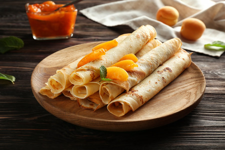 Plate with tasty pancakes and apricots on wooden tableの写真素材
