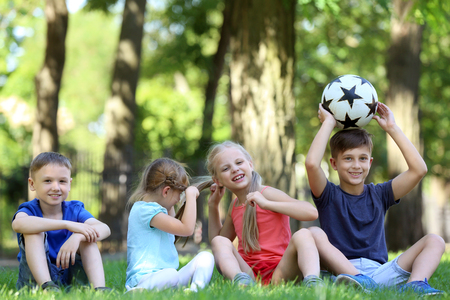 Cute little children sitting on green grass in parkの写真素材