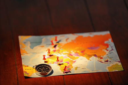 World map with compass and pushpins on tableの写真素材