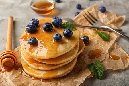 Delicious pancakes with berries and honey on light tableの写真素材