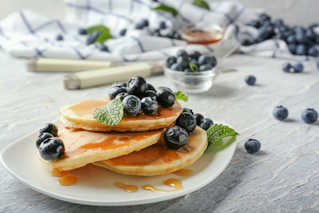 Plate with delicious pancakes and berries on wooden table