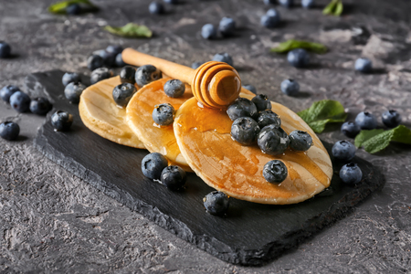 Slate board with delicious pancakes, honey and berries on grunge tableの写真素材