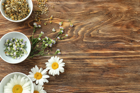 Bowls with beautiful fresh and dry chamomiles on wooden backgroundの写真素材