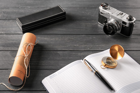 Vintage compass with photo camera, map and notebook on wooden tableの写真素材