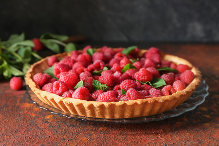 Tasty pie with fresh raspberries on color textured table
