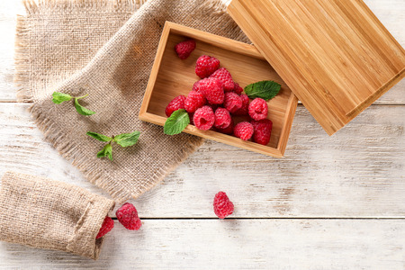 Wooden box with sweet ripe raspberries on tableの写真素材