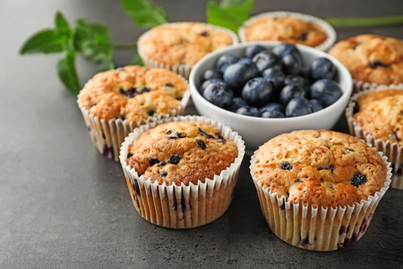 Tasty blueberry muffins and bowl with fresh berries on table, closeupの写真素材