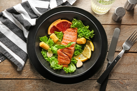 Bowl with fresh salad and fish on wooden tableの写真素材