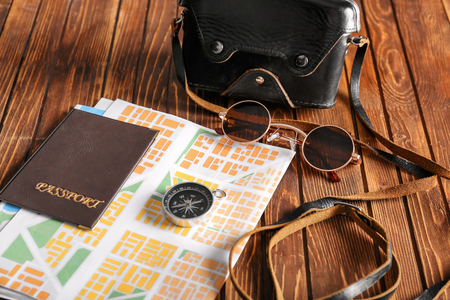 Passport with map, compass, sunglasses and photo camera on wooden tableの写真素材