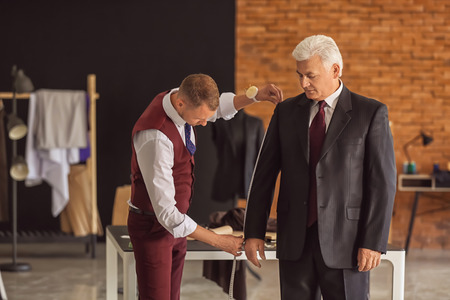 Young tailor taking client's measurements in atelier