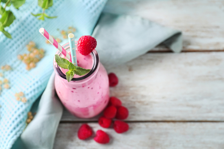 Glass bottle with tasty raspberry smoothie on wooden tableの写真素材