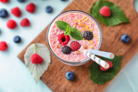 Glass with tasty raspberry smoothie on light tableの写真素材