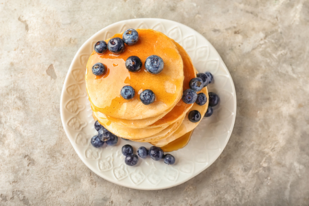 Plate with delicious pancakes and berries on light tableの写真素材