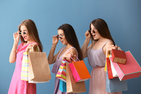 Beautiful young women with shopping bags on color backgroundの写真素材