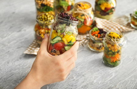Woman holding mason jar with vegetable saladの写真素材