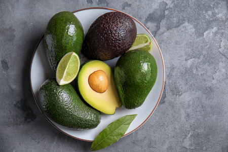 Plate with fresh ripe avocados and lime on grey textured backgroundの写真素材