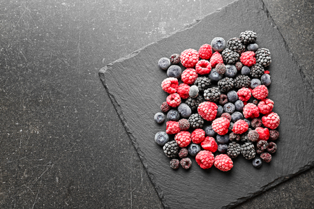 Slate plate with delicious frozen berries on grey backgroundの写真素材