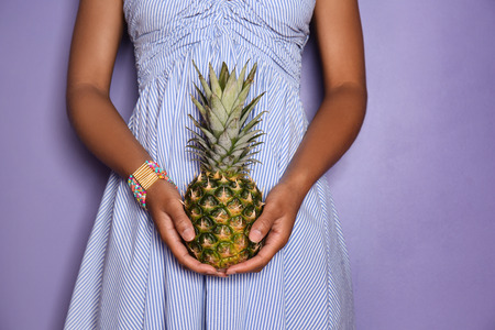 Beautiful African-American woman with pineapple on color background, closeupの写真素材