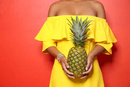 Beautiful African-American woman with pineapple on color background