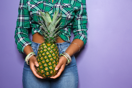 Beautiful African-American woman with pineapple on color background