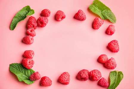 Frame made of sweet ripe raspberries on color background