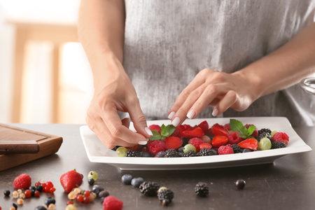 Woman serving fresh berries on plateの写真素材