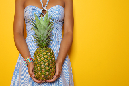 Beautiful African-American woman with pineapple on color backgroundの写真素材