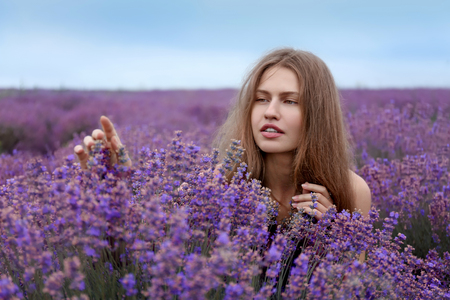 Beautiful young woman in lavender field on summer dayの写真素材