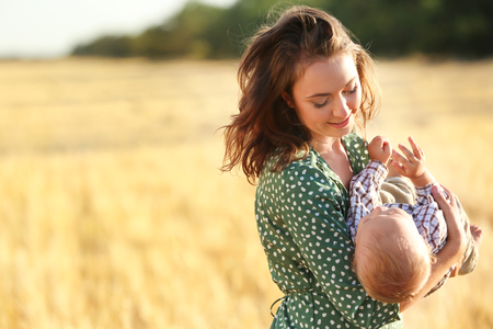 Beautiful woman playing with her little son in wheat field on summer dayの写真素材