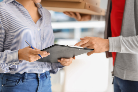 Woman signing document to confirm receipt of order from food delivery companyの写真素材