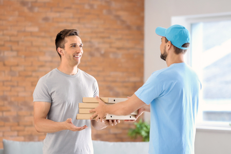 Man delivering pizza to customer indoorsの写真素材
