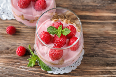 Delicious dessert with raspberries in glasses on wooden tableの写真素材