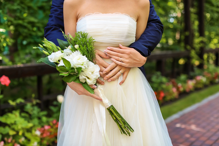 Happy newlyweds with beautiful wedding bouquet outdoorsの写真素材