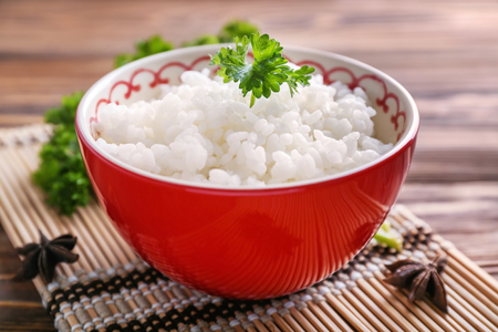 Bowl with boiled white rice on wooden tableの写真素材