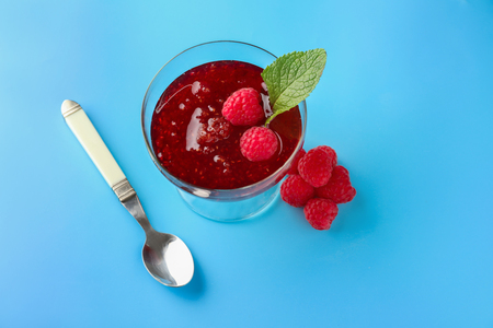 Glass dessert bowl with sweet raspberry jam on color backgroundの写真素材