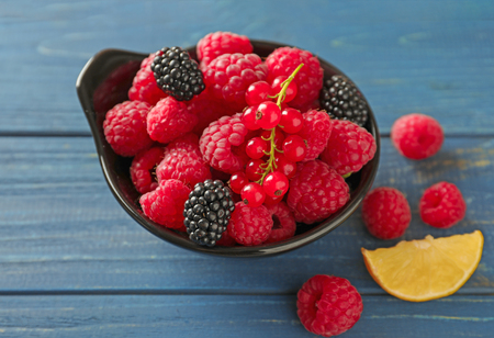 Bowl with fresh ripe berries on wooden table