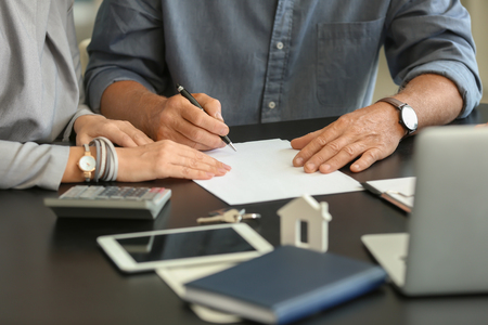 Mature couple signing document in estate agent's officeの写真素材