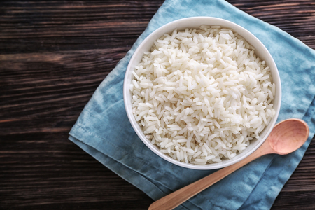 Bowl with boiled white rice on wooden tableの写真素材