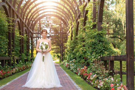 Beautiful young bride with wedding bouquet outdoorsの写真素材