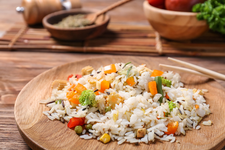Plate of tasty rice with vegetables on wooden table, closeupの写真素材