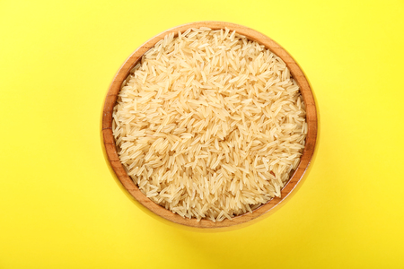 Wooden bowl with raw brown rice on color backgroundの写真素材