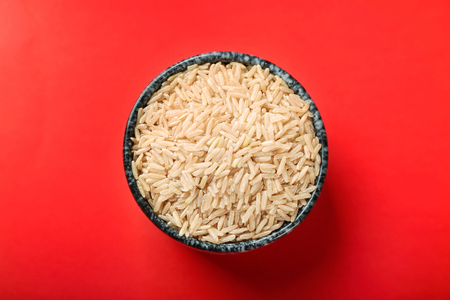 Bowl with raw brown rice on color backgroundの写真素材