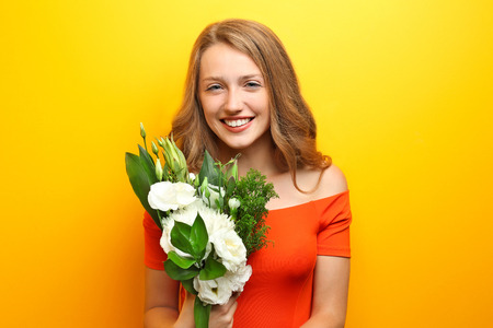 Young woman with beautiful flowers on color backgroundの写真素材
