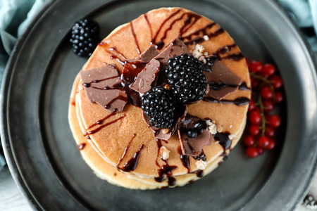Tasty homemade pancakes with chocolate and blackberries on plate, closeup