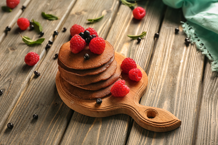 Tasty chocolate pancakes with berries on wooden tableの写真素材