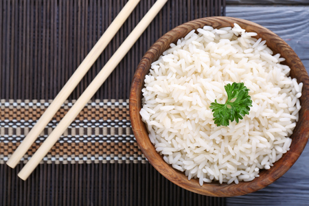 Bowl with boiled white rice on tableの写真素材