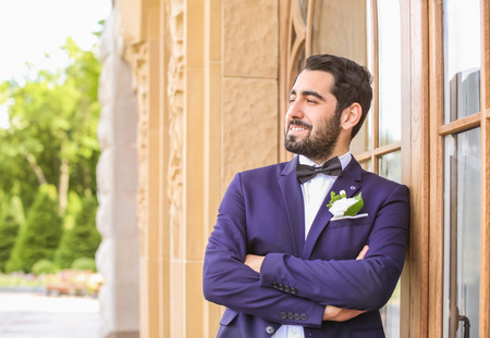 Handsome young groom in elegant suit outdoors