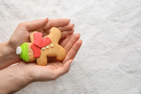 Woman holding Christmas cookie on snowy backgroundの写真素材
