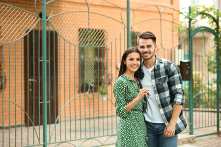 Young happy couple with key near their new house outdoorsの写真素材