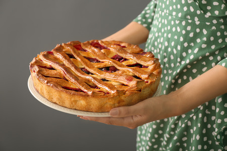 Woman holding tasty pie with berries on grey backgroundの写真素材